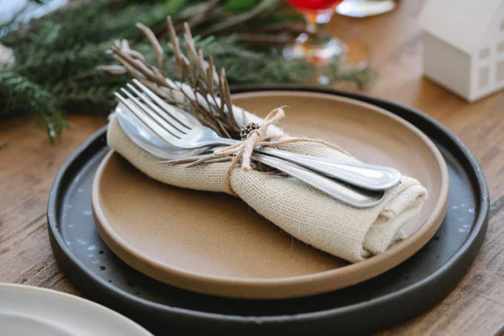 imagem em que está um prato da mesa de natal com talheres presos em um guardanapo de pano.
