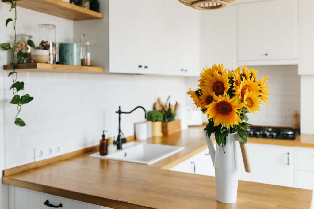 um vaso de girassóis no foco da fotografia indicando um ambiente de cozinha atrás