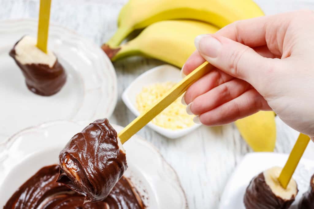 uma mão fazendo um doce de banana com chocolate