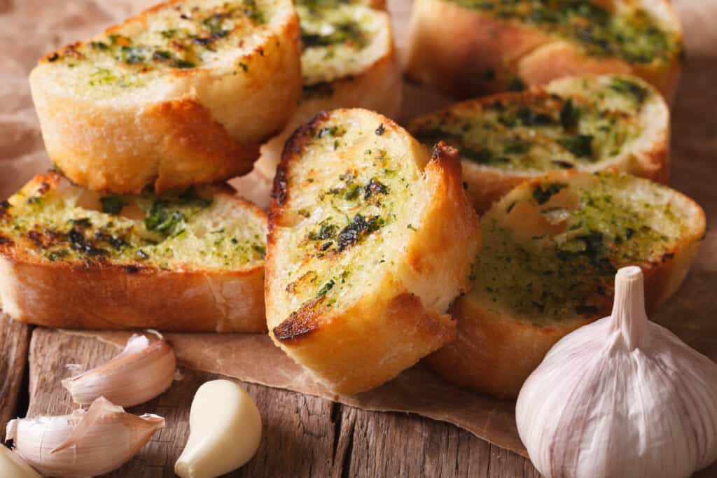 pão de alho com cheiro verde acima de uma tábua e um alho