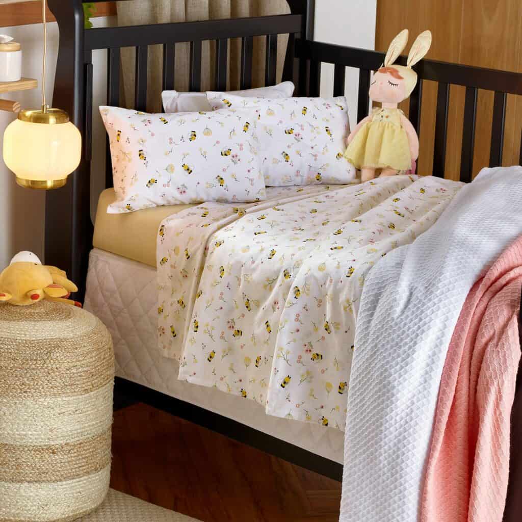 um quarto infantil com roupa de cama neutra de abelhas