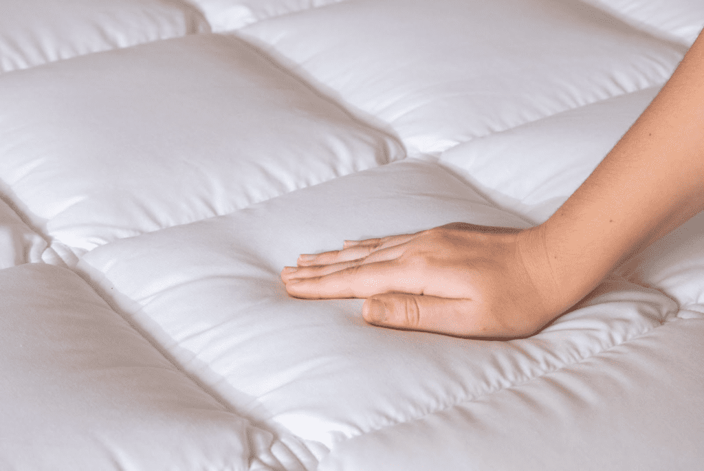 uma mão afofando o melhor pillow top branco, liso e matelado