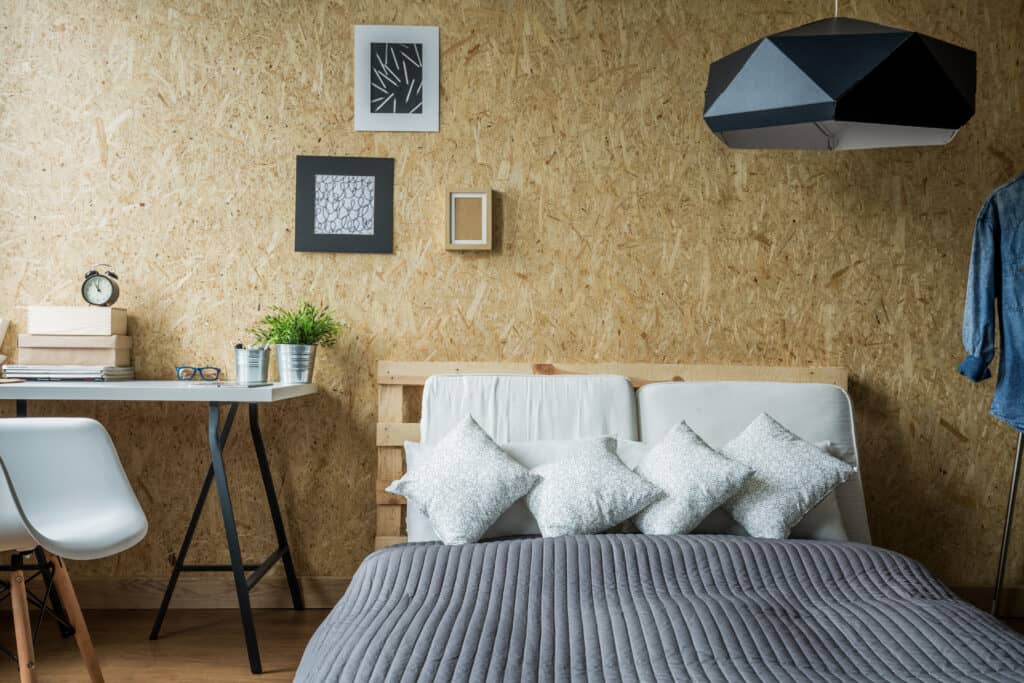 um quarto com parede amadeirada com uma cama e decorações em branco e cinza